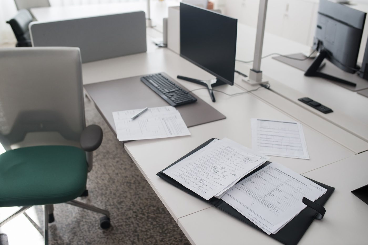 A tidy open-plan office with desks, monitors and paperwork